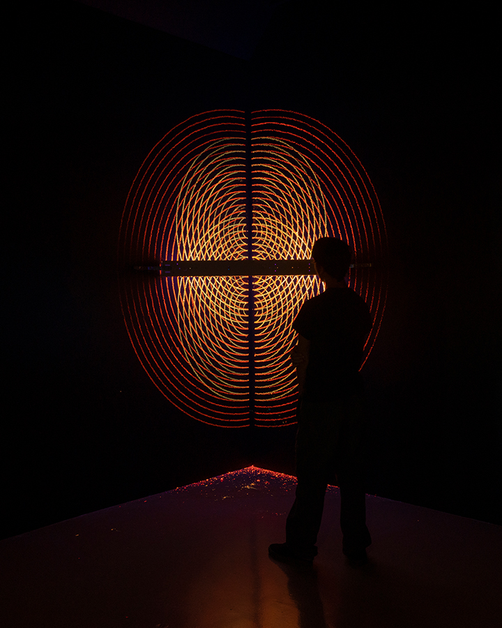 Silhouette of a young boy standing in front of an illuminated orange and yellow hologram. 