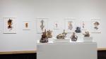 Ceramic flower sculptures in front of gouache paintings.