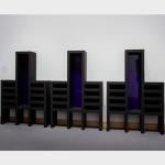 Three cabinet like black sculptures with blue glass back panels.